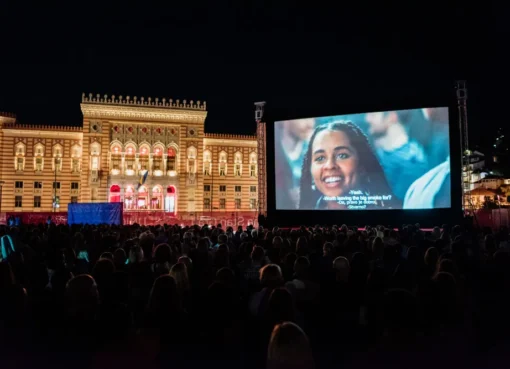 People watching a movie outdoors under the night sky at a film festival.
