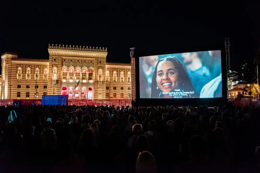 People watching a movie outdoors under the night sky at a film festival.