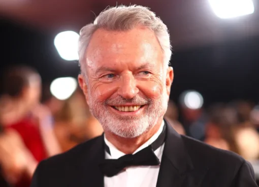 Sam Neill smiling warmly, looking thoughtful.