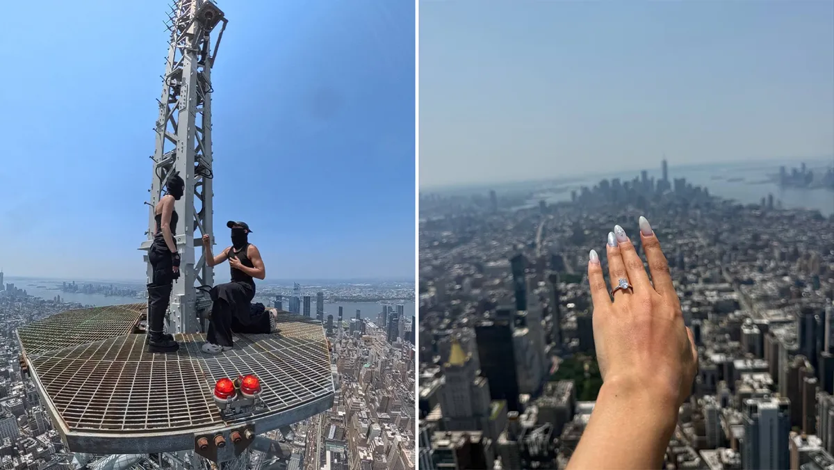Two people standing on top of a very tall building with the city below