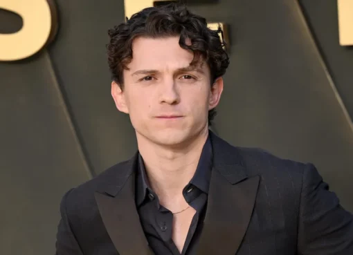 Tom Holland smiling on a movie red carpet.