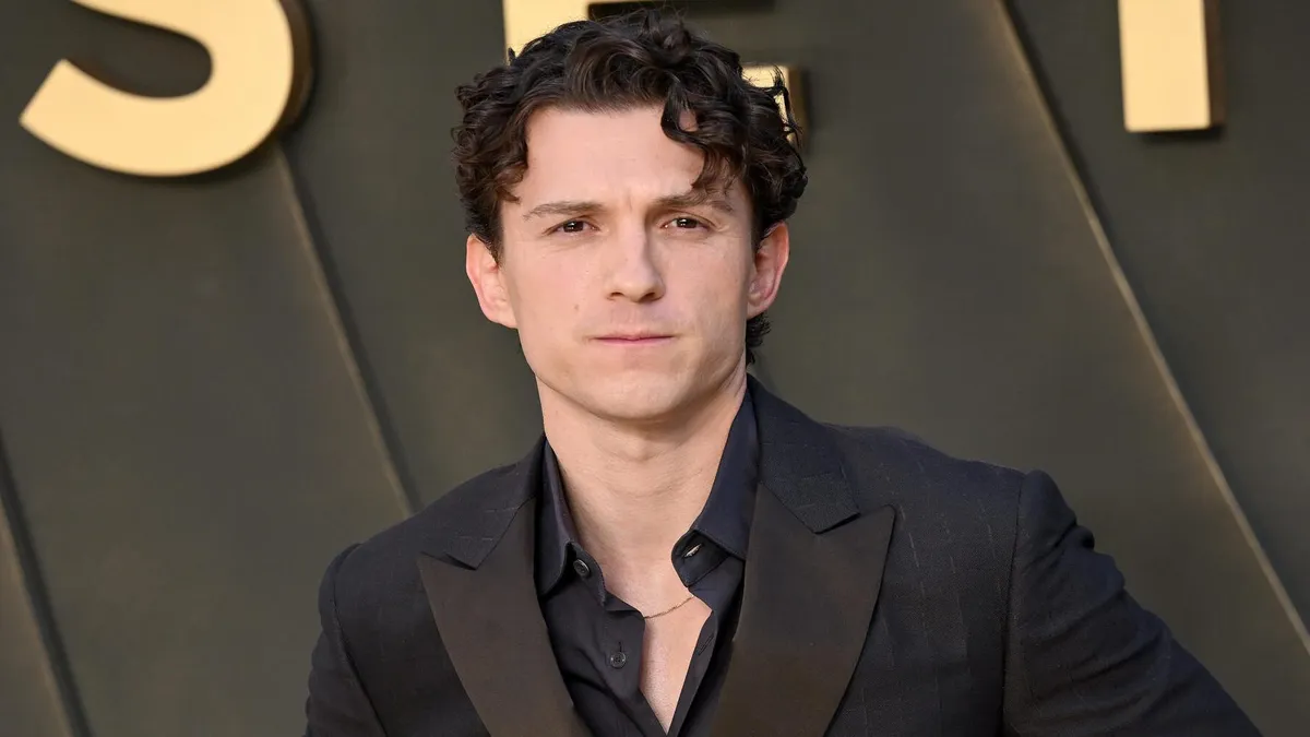 Tom Holland smiling on a movie red carpet.