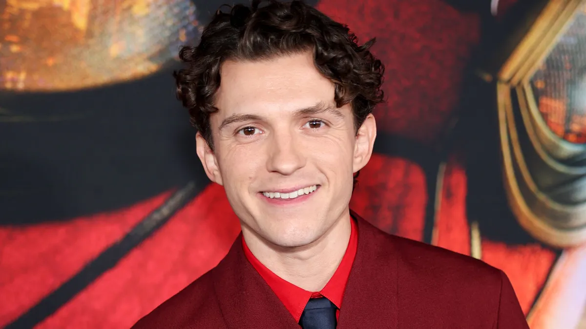 Tom Holland smiling on the red carpet at the Spider-Man premiere