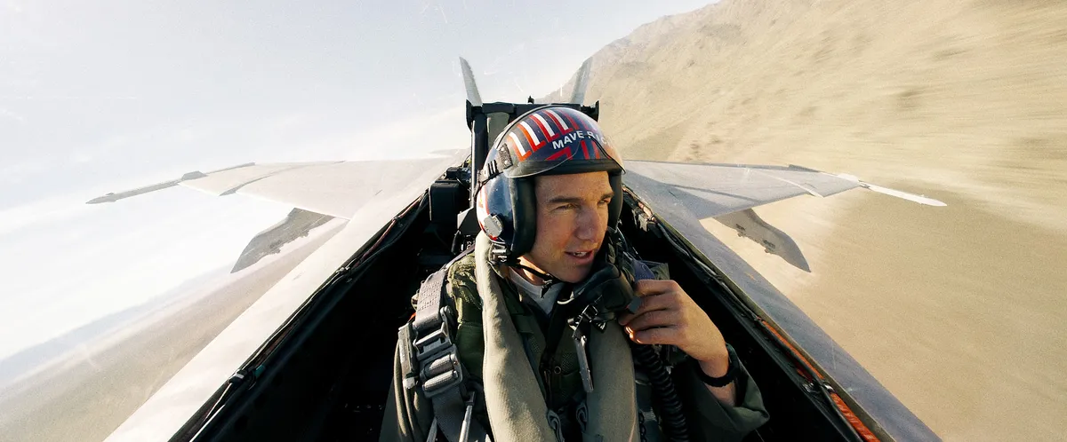 An artistic rendering of a Top Gun-themed attraction or building in Las Vegas, possibly with fighter jets or iconic imagery, near the famous "Welcome to Fabulous Las Vegas" sign.