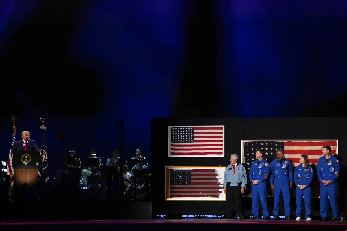 Donald Trump speaking on a stage decorated with historical American flags and veterans.