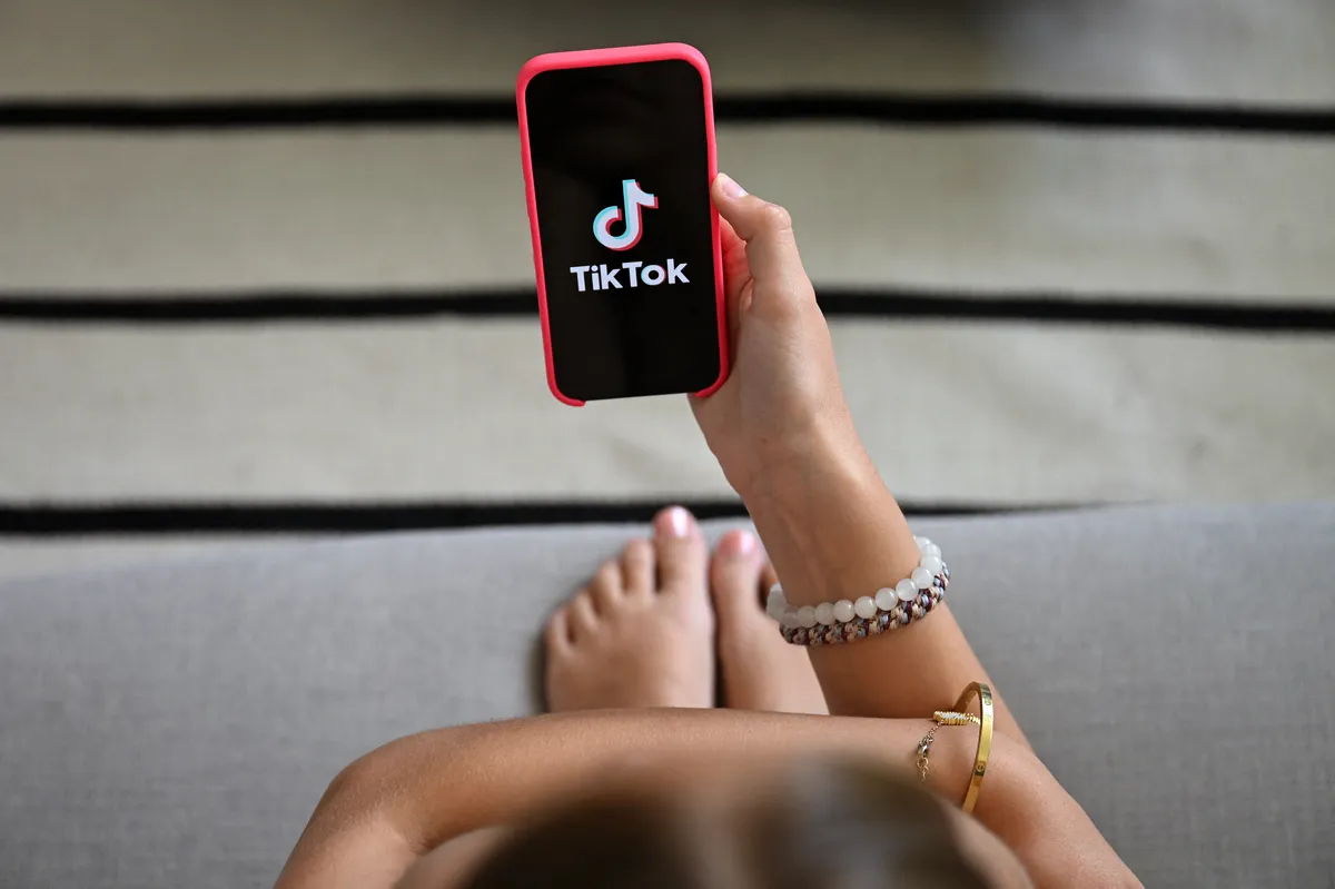 A phone screen displaying the TikTok app logo, against a slightly blurred background, suggesting digital content.