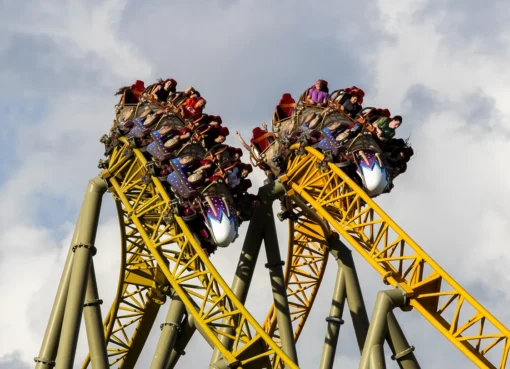 A colorful roller coaster track against a bright blue sky at a theme park.