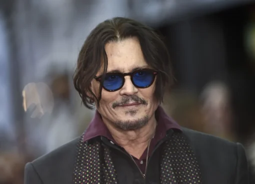 Johnny Depp dressed as Ebenezer Scrooge at Comic-Con, walking past a shop called 'Scrooge and Marley.'