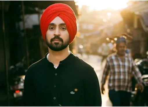 Diljit Dosanjh looking thoughtful and charismatic, possibly on a stage or at an event, with a slight smile.