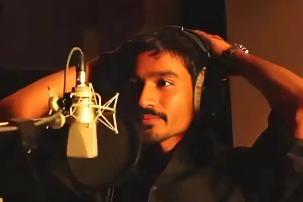 Dhanush looking thoughtful on a film set, showing a reflective moment.