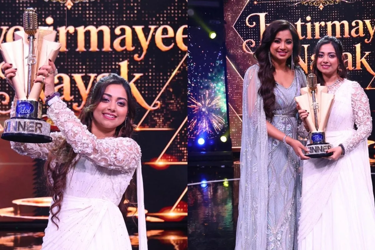 Jyotirmayee Nayak smiling and holding the Indian Idol 16 trophy with confetti falling around her.