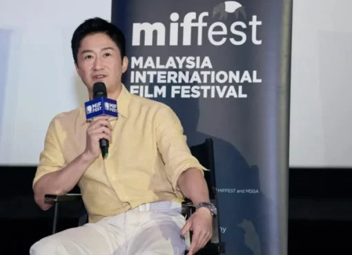Wu Jing smiling and holding an award at the Malaysia International Film Festival.