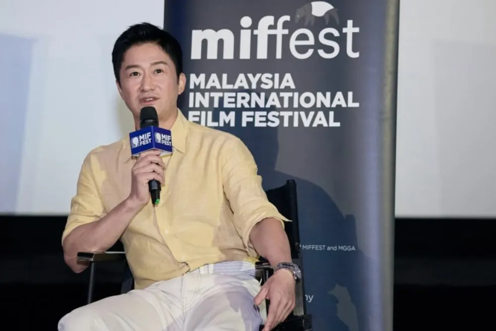 Wu Jing smiling and holding an award at the Malaysia International Film Festival.