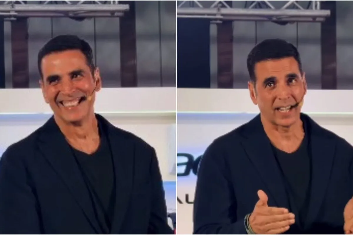 Akshay Kumar laughing heartily at a press conference, looking amused and relaxed.