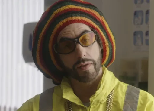 Ali G in his signature yellow tracksuit and beanie, looking surprised or defiant.