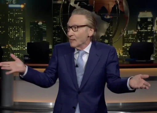 Bill Maher on stage looking at the audience with an uncomfortable expression on 'Real Time'.