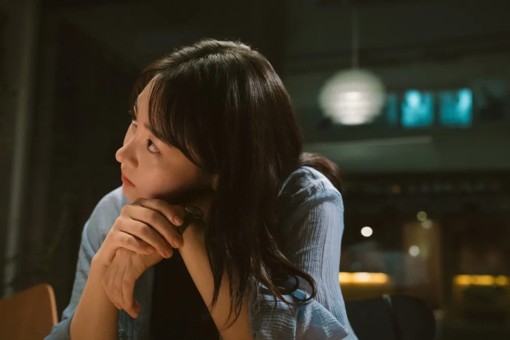 A dimly lit cafe interior with soft lighting, a small table and two chairs, hinting at intimate conversations.