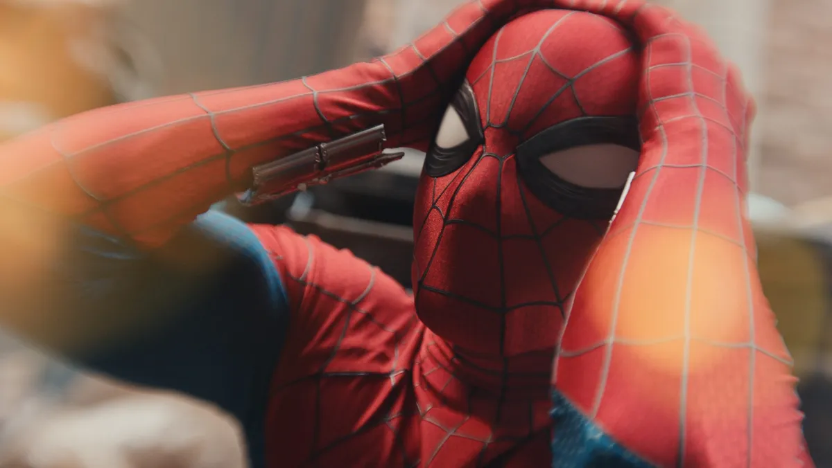 Spider-Man swinging through a city, with a pixelated or glitchy visual effect representing a movie leak.