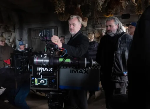 Christopher Nolan, the film director, speaking into a microphone with a serious expression.