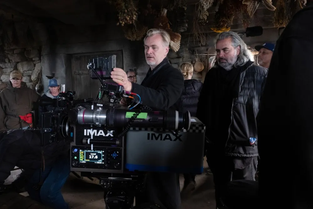 Christopher Nolan, the film director, speaking into a microphone with a serious expression.