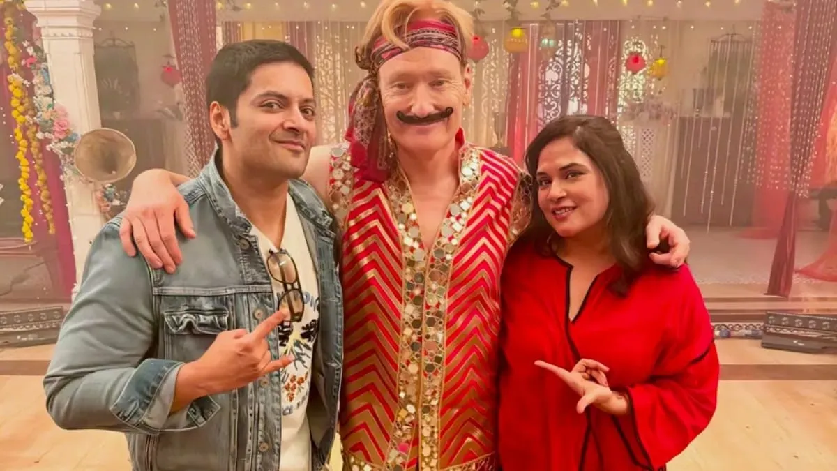 Conan O'Brien smiling with Richa Chadha and Ali Fazal, hinting at their India adventure.