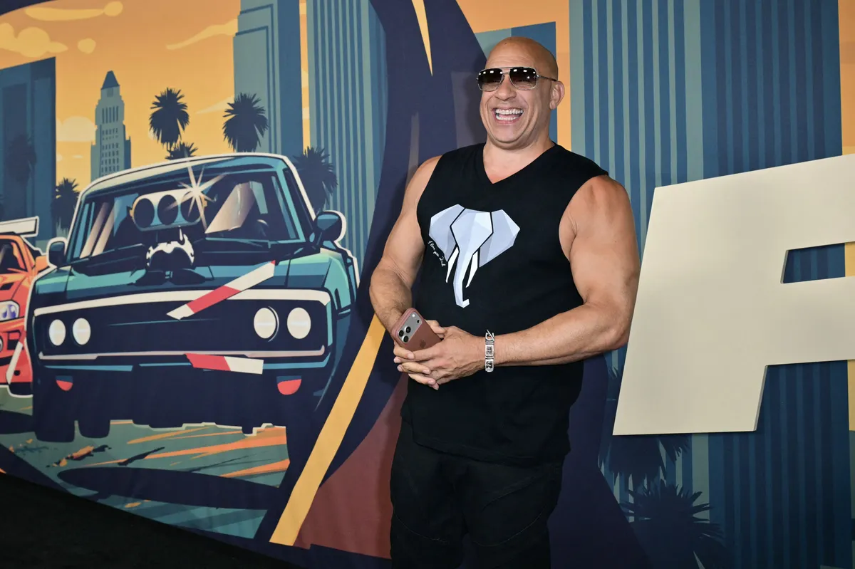 Vin Diesel smiling confidently and giving a slight smirk at a public event.