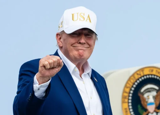 President Donald Trump speaking at a podium, possibly with a subtle film or Hollywood backdrop.