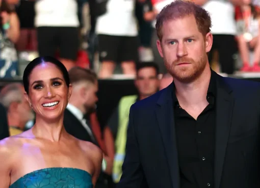 Prince Harry and Meghan Markle smiling and waving at an event.