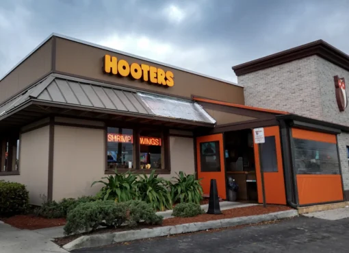 A film clapperboard over a Hooters logo with a beach background.