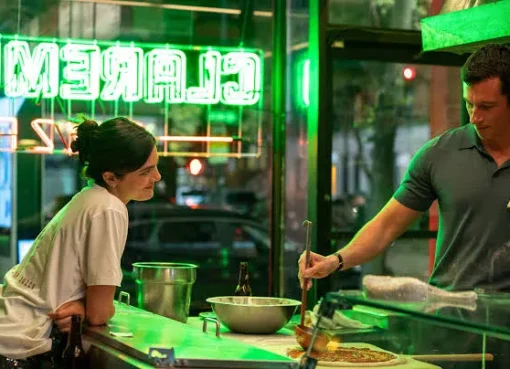 Monica Barbaro and Callum Turner looking attractive in a movie scene.