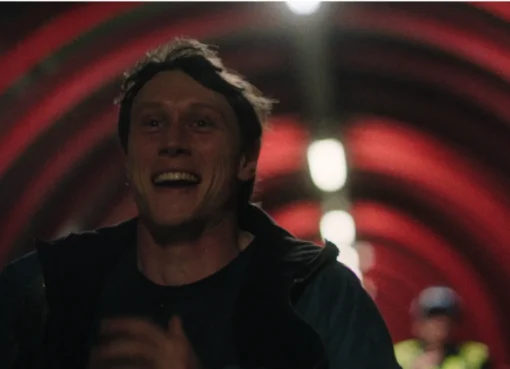 George MacKay in a dramatic movie scene, looking thoughtful.