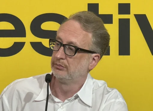 James Gray smiling at the Locarno Film Festival with a banner in the background.