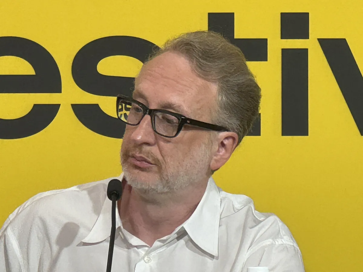James Gray smiling at the Locarno Film Festival with a banner in the background.