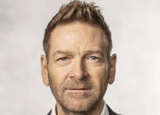 Kenneth Branagh smiling and holding an award on stage at the Edinburgh International Film Festival.