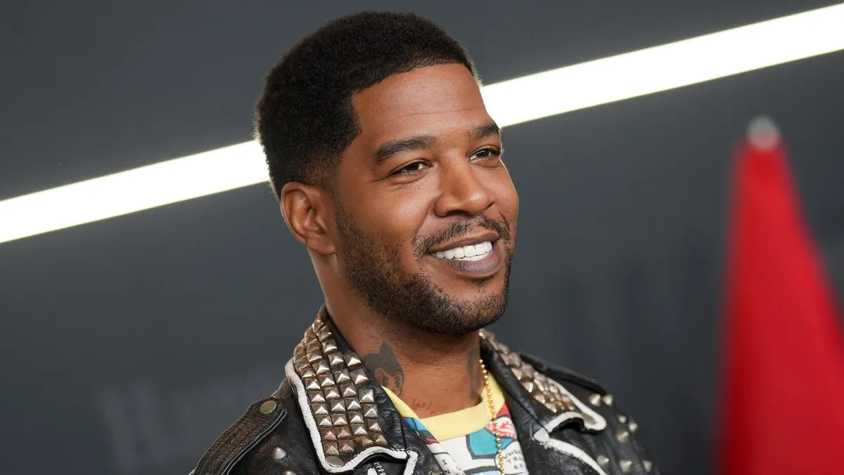 Kid Cudi smiling, perhaps on a film set.
