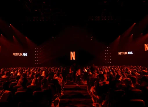 A person holding a phone showing the Netflix app with a colorful ad overlay.