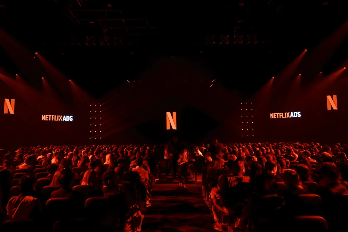 A person holding a phone showing the Netflix app with a colorful ad overlay.