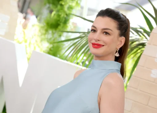 Anne Hathaway smiling and looking emotional at an awards ceremony, holding a Disney Legend award.