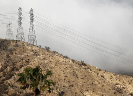 Photo of a burned transmission tower with smoke in the background.