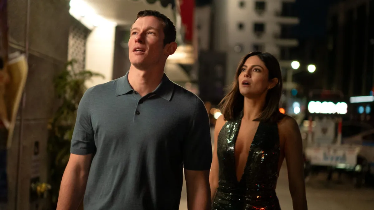 A couple looking lovingly at each other under city lights.
