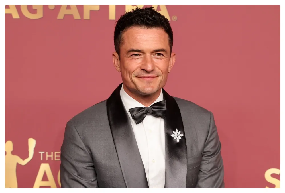 Orlando Bloom smiling at a film festival event, looking smart and happy.