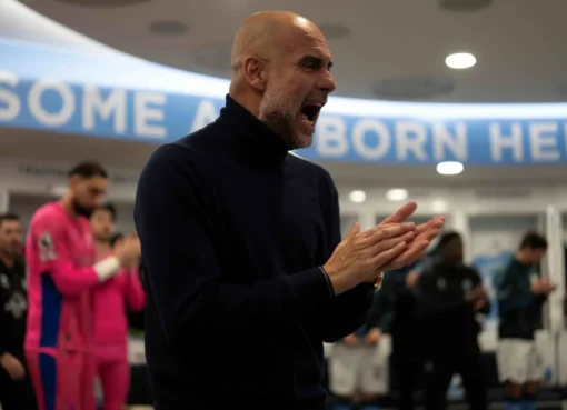 Pep Guardiola in a suit, looking focused.
