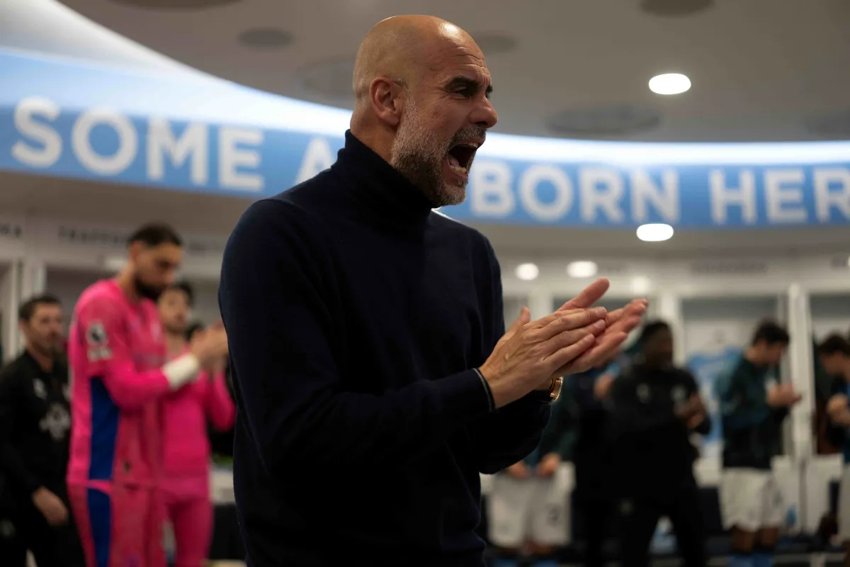 Pep Guardiola in a suit, looking focused.
