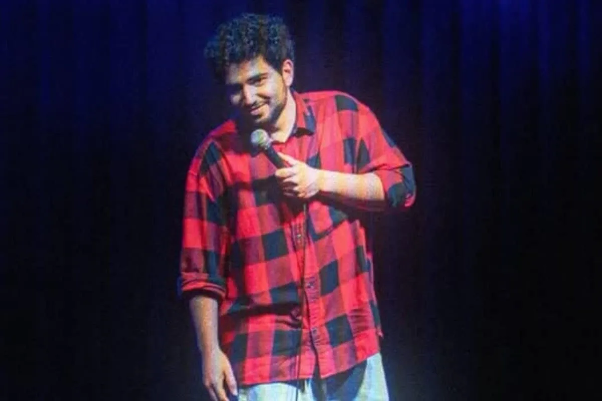 Comedian Samay Raina performing stand-up comedy on a dark stage