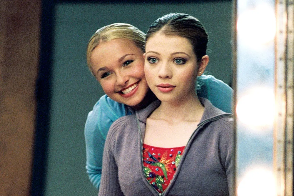 Hayden Panettiere and Michelle Trachtenberg smiling brightly in their ice skating costumes from the movie 'Ice Princess'.