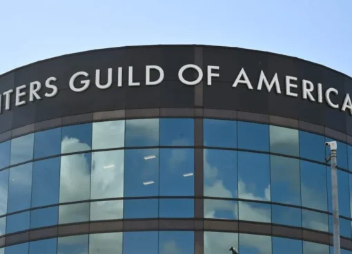 A dramatic image showing a studio building being packed up, with a stern-looking WGA logo overlaid.