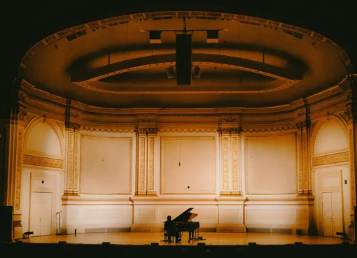 Paul Thomas Anderson and Cameron Winter on stage at Carnegie Hall, bathed in warm stage lights.