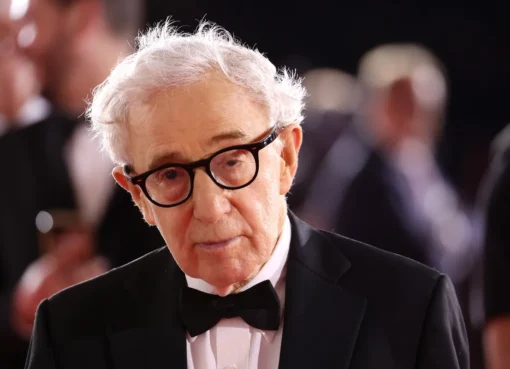 Woody Allen smiling, with a subtle backdrop hinting at a Spanish street scene.