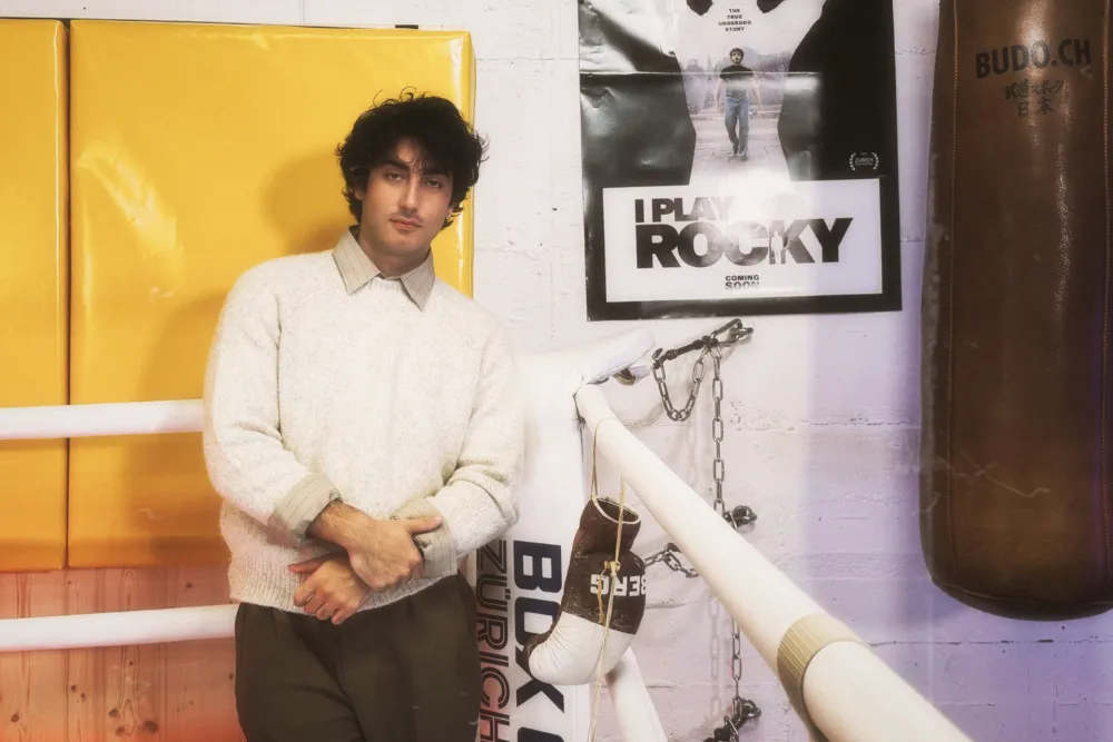 Anthony Ippolito in a boxing ring, wearing a cream pullover and pressed shirt.