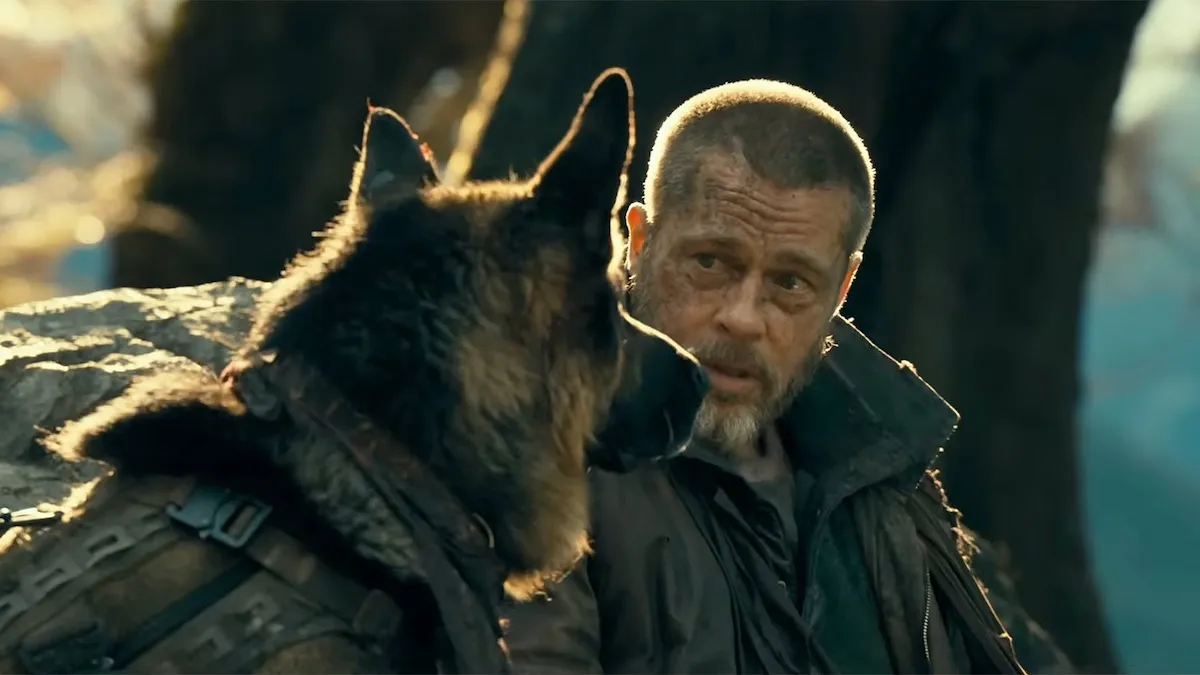 Brad Pitt looking determined alongside a German Shepherd dog in a wild, snowy forest.